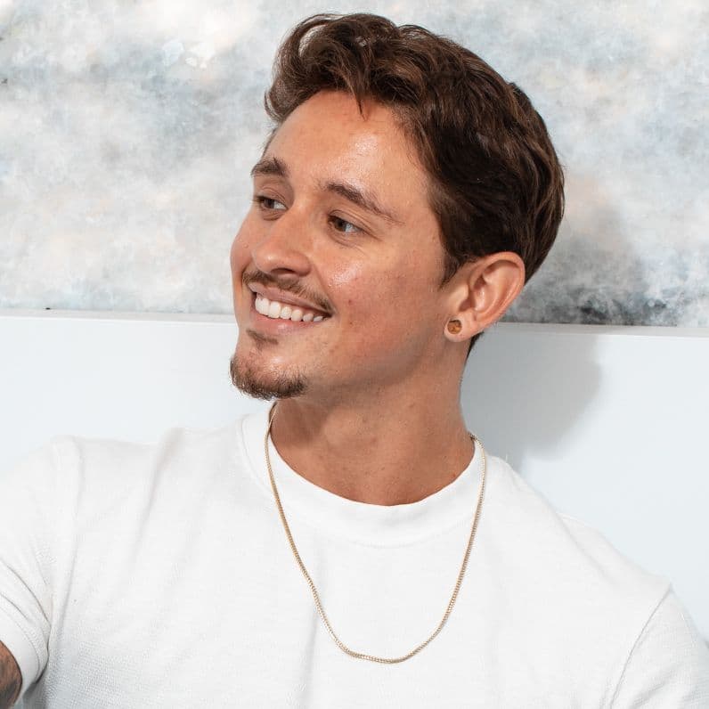 Smiling man in a white shirt seated against a soft abstract background in a care setting