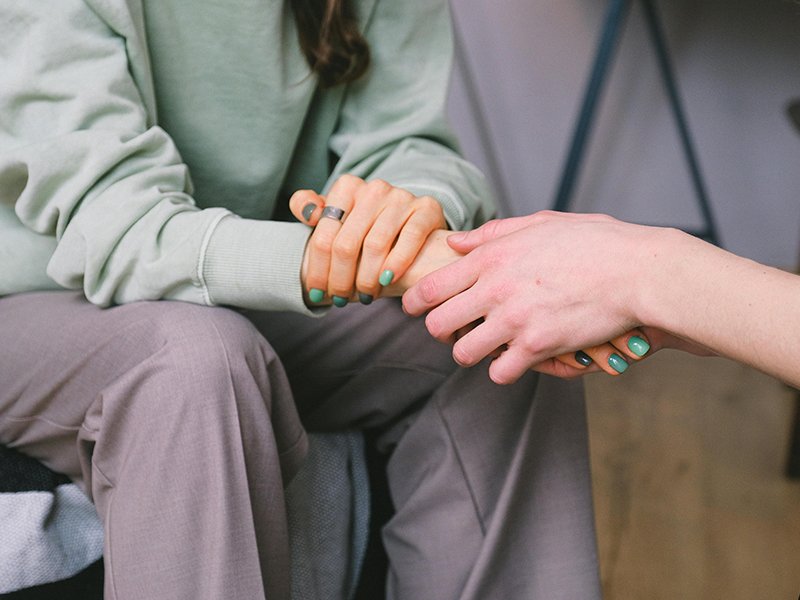 Photo of seated people holding hands