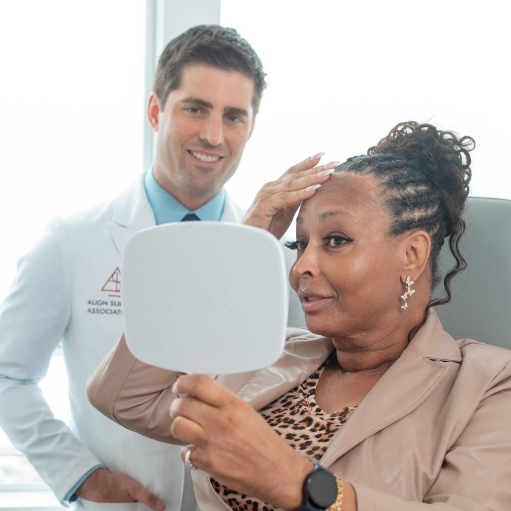 Dr. Mittermiller reviewing results with a patient holding a hand mirror