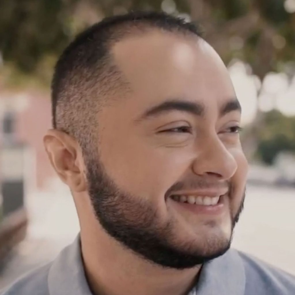 Smiling man shown in close-up outdoors.