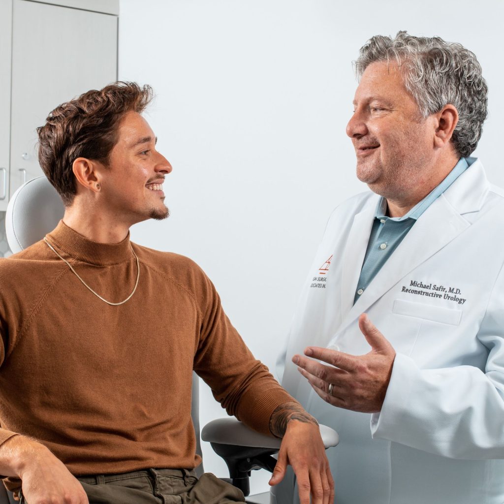 Doctor speaking with a seated patient in an exam room.