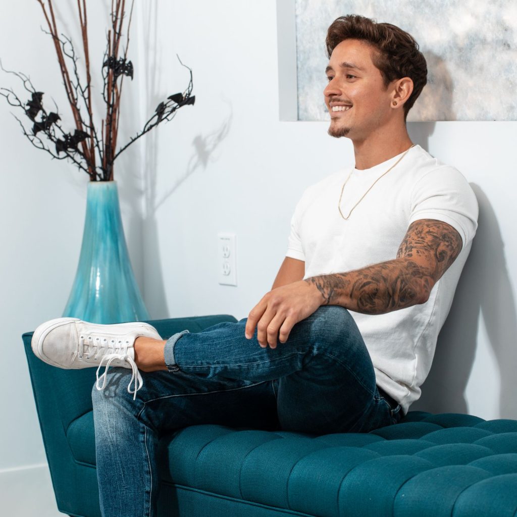 Smiling patient seated on a teal bench in a consultation room.