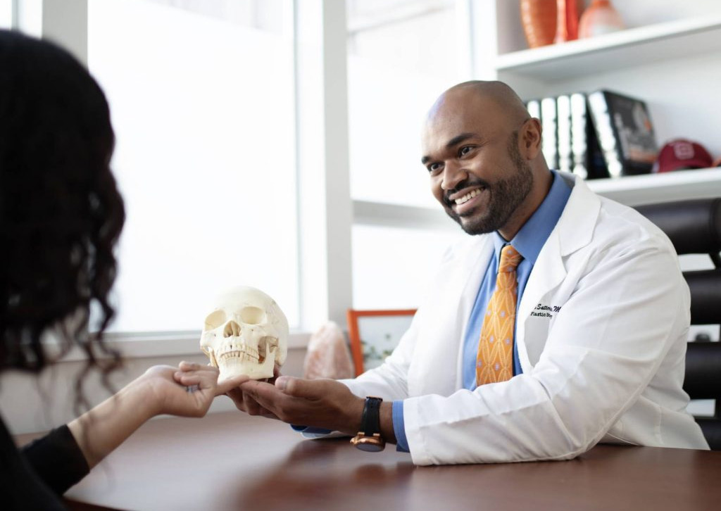 Dr. Thomas Satterwhite explaining an anatomical skull model during a consultation